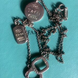 Tiffany & Co. Silver Multi-Charm Necklace on Tiffany Blue bag.